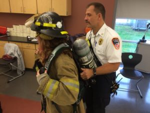 fire instructor strapping in student to firefighter unifiorm