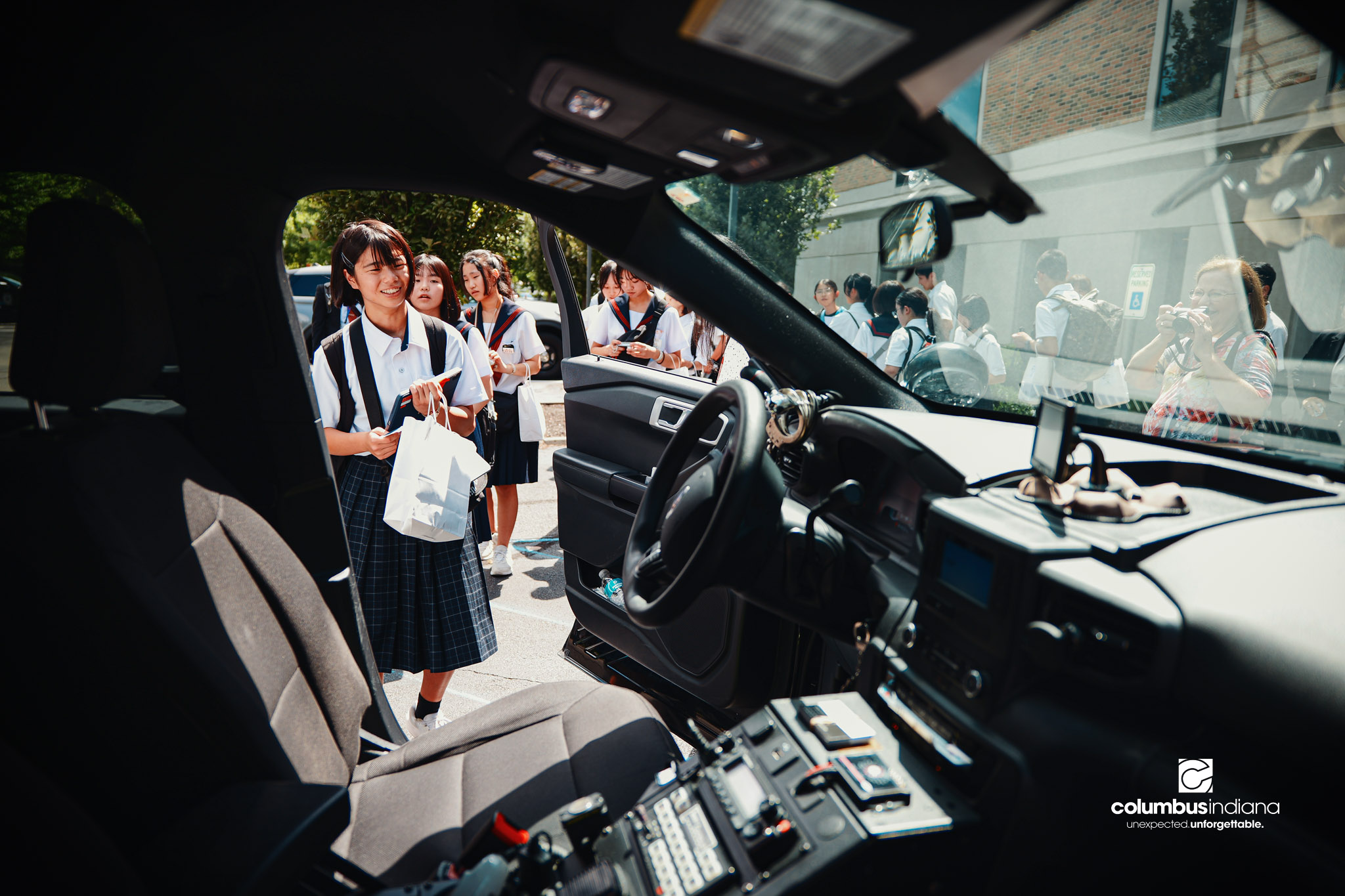 A delegation of students and school officials from Miyoshi-Minami Junior High School line up operate the lights and sirens in Columbus Police Lt. Skylar Berry’s police cruiser during a tour of the Columbus Police Department in Columbus, Ind., Thurs