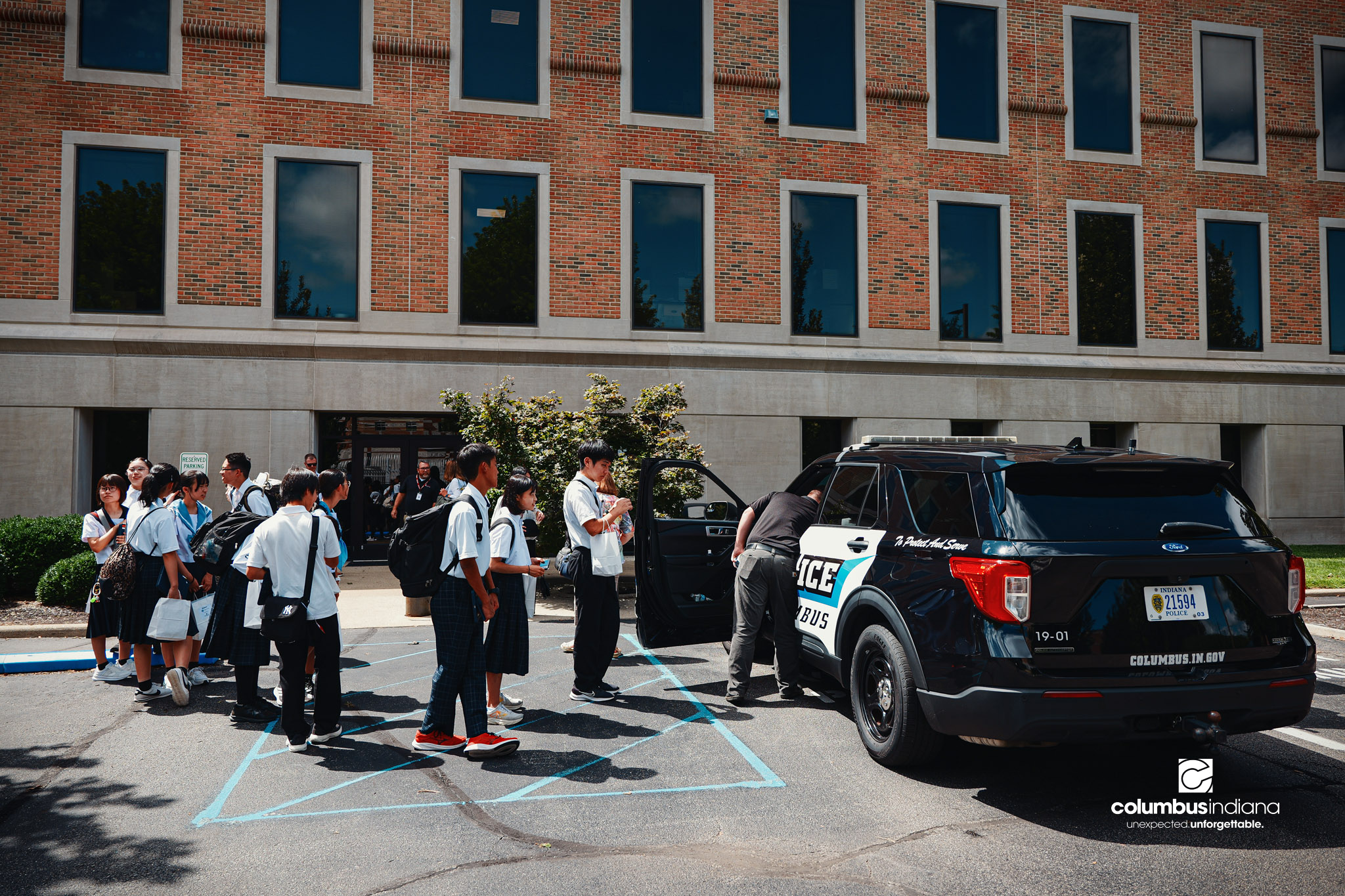 A delegation of students and school officials from Miyoshi-Minami Junior High School line up operate the lights and sirens in Columbus Police Lt. Skylar Berry’s police cruiser during a tour of the Columbus Police Department in Columbus, Ind., Thurs