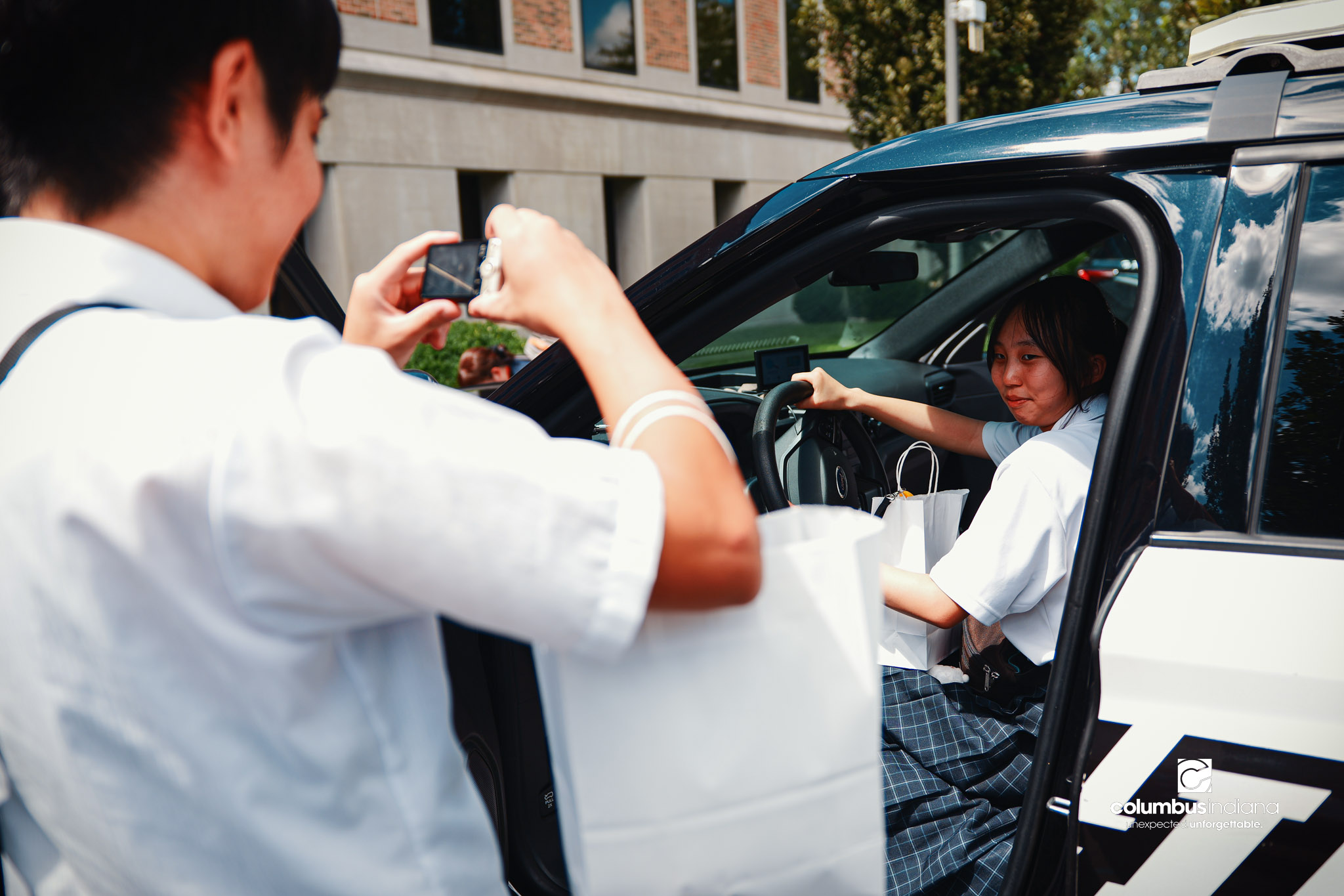 Miyoshi-Minami Junior High student Takumi Hirashita, left, takes photos as his classmate Nozomi Kajiya sits in Columbus Police Lt. Skylar Berry’s police cruiser during a tour of the Columbus Police Department in Columbus, Ind., Thursday, Aug. 20, 2