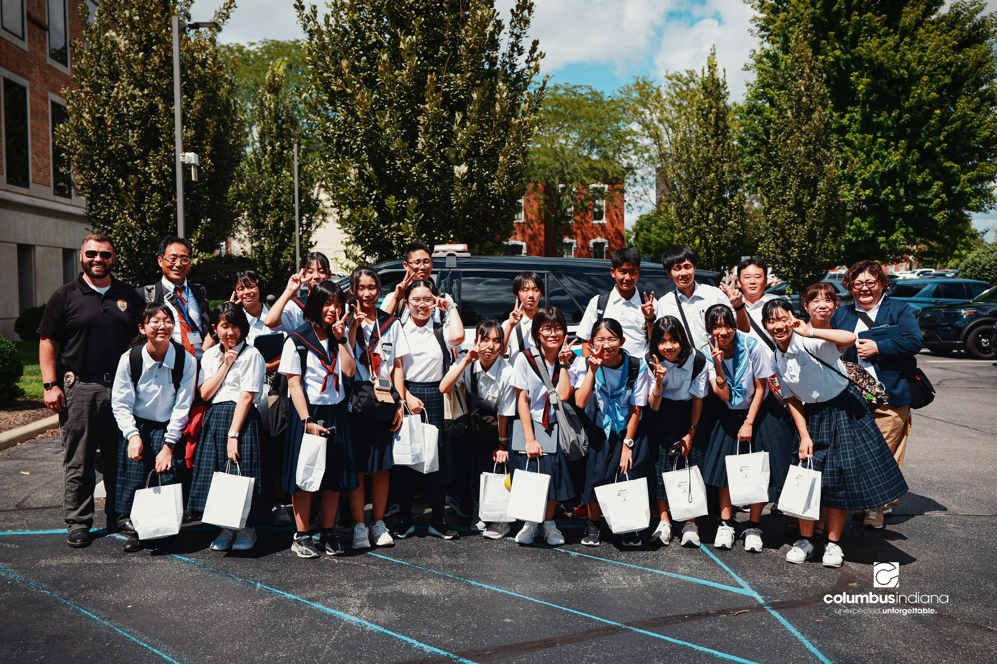 A delegation of students and school officials from Miyoshi-Minami Junior High School pose for a photo with Columbus Police Lt. Skylar Berry during a tour of the Columbus Police Department in Columbus, Ind., Thursday, Aug. 20, 2026. Miyoshi is Columbu