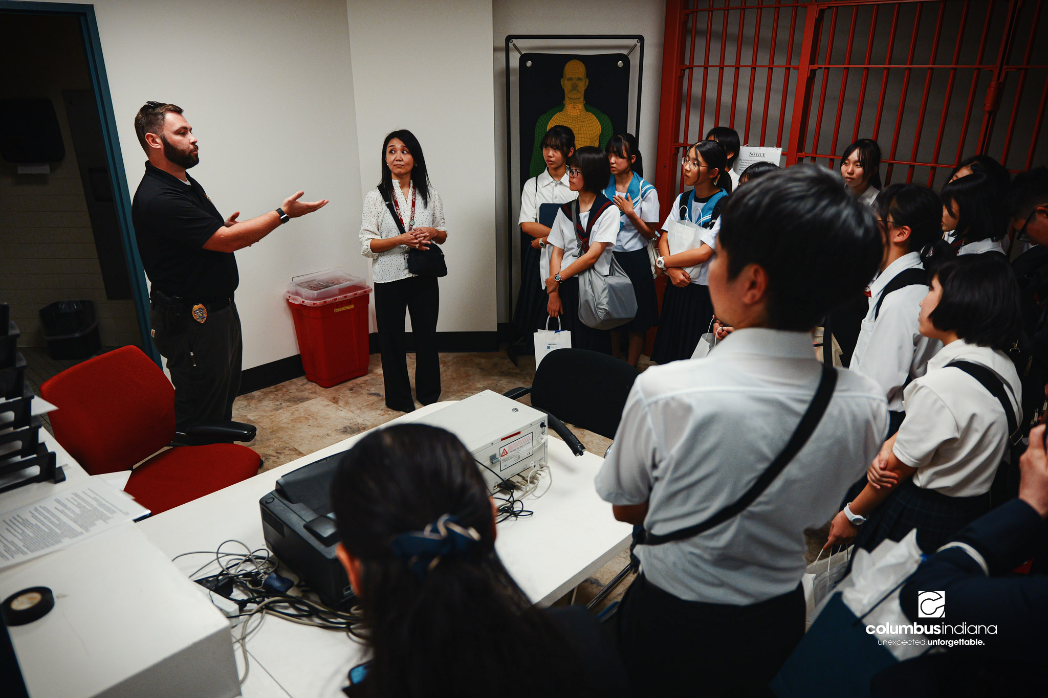 Maya Sutherland, center, with BCSC, translates as Columbus Police Lt. Skylar Berry guides a delegation of students and school officials from Miyoshi-Minami Junior High School on a tour of the Columbus Police Department in Columbus, Ind., Thursday, Au