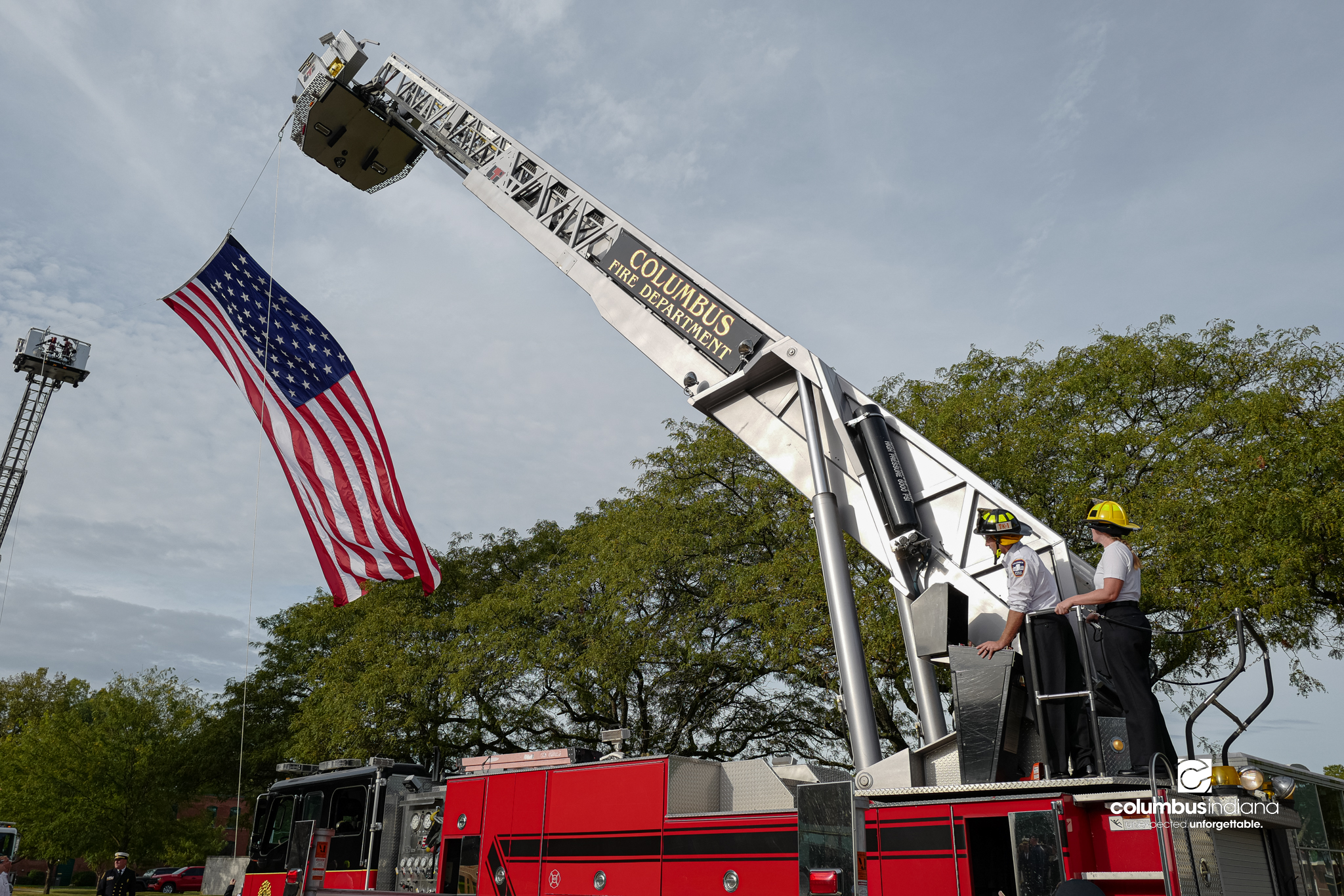 Columbus firefighters lower a large, garrison-style American flag after a ceremony to commemorate the 25th anniversary of Sept. 11, at Columbus City Hall in Columbus, Ind., Friday, Sept. 11, 2026.