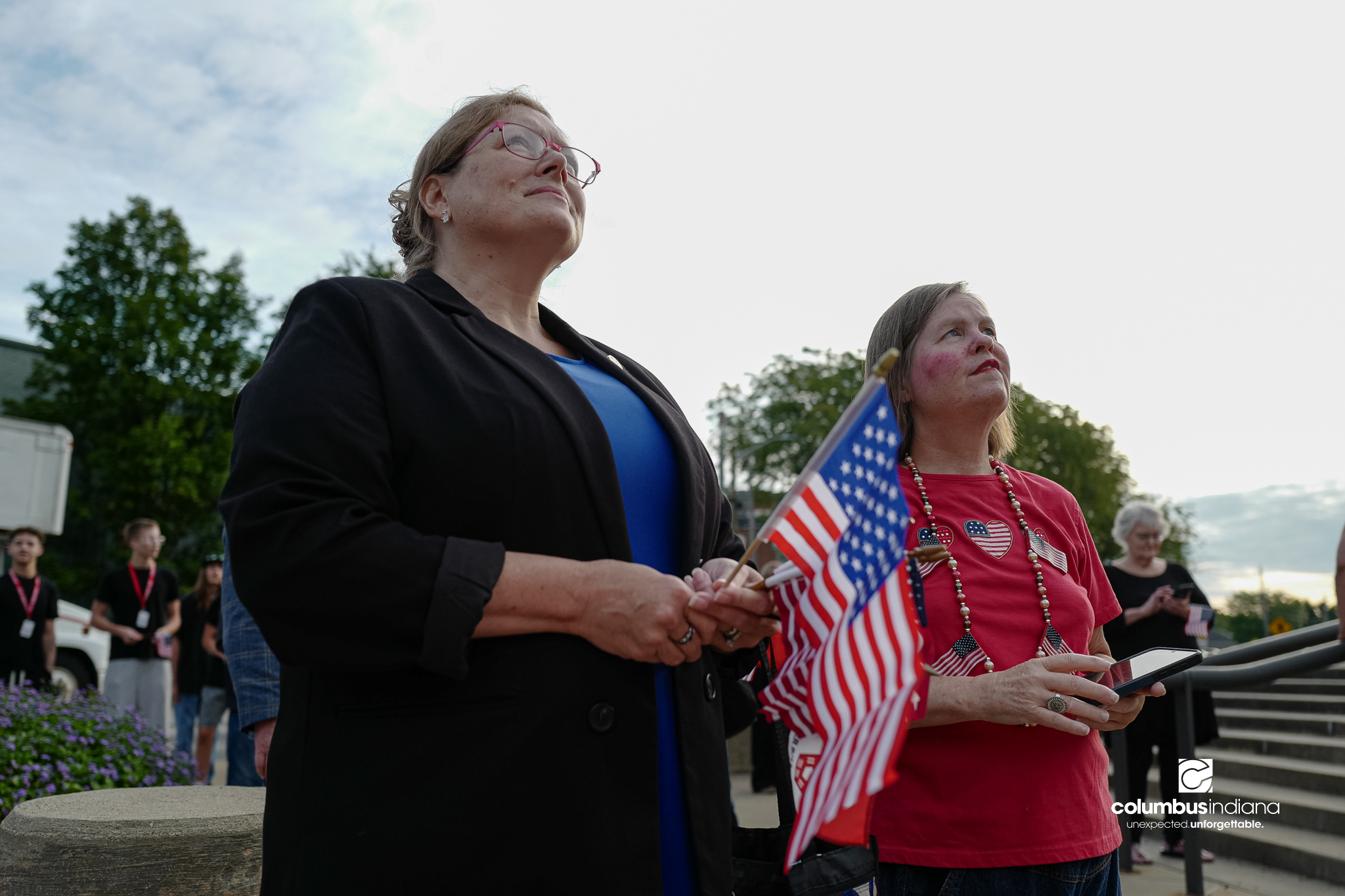 Spectators look on as a large American flag is raised before a ceremony to commemorate the 25th anniversary of Sept. 11, at Columbus City Hall in Columbus, Ind., Friday, Sept. 11, 2026.