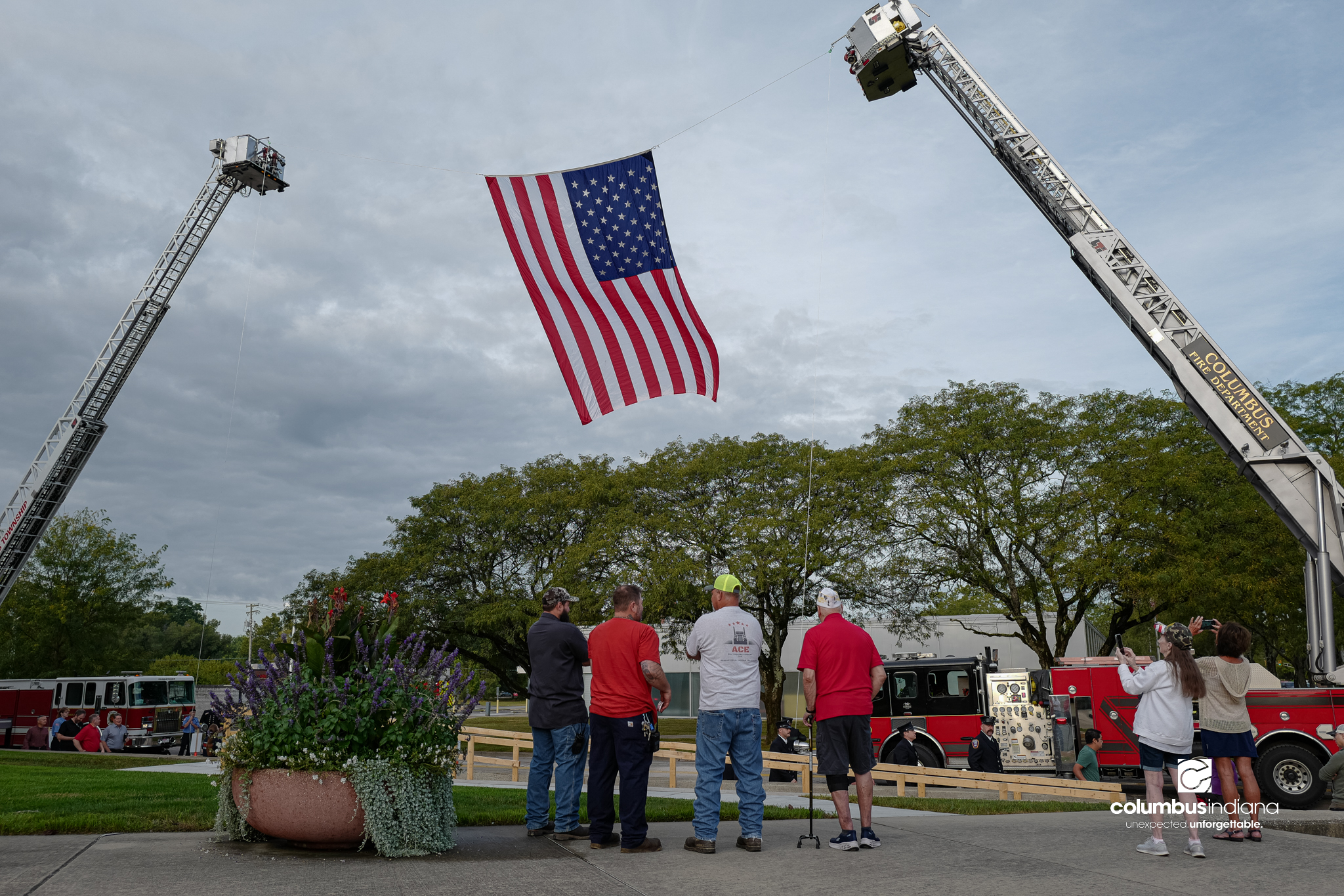 Spectators look on as a large American flag is raised before a ceremony to commemorate the 25th anniversary of Sept. 11, at Columbus City Hall in Columbus, Ind., Friday, Sept. 11, 2026.