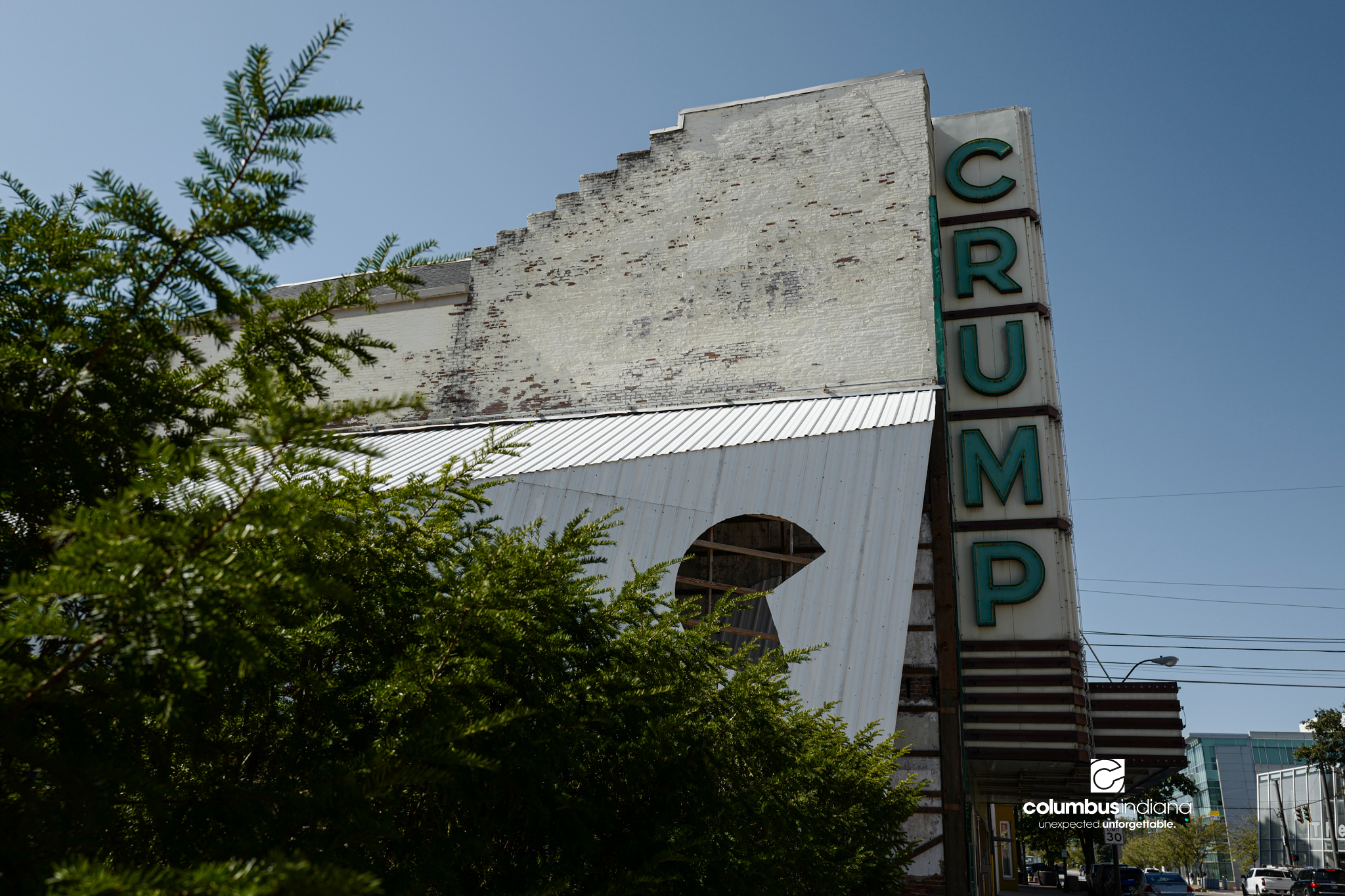 An exterior view of an old, historic theater in Columbus, Indiana. The theater is made of brick and concrete. The marquee has a giant sign that spells out the name Crump. The building is named the Crump Theatre.