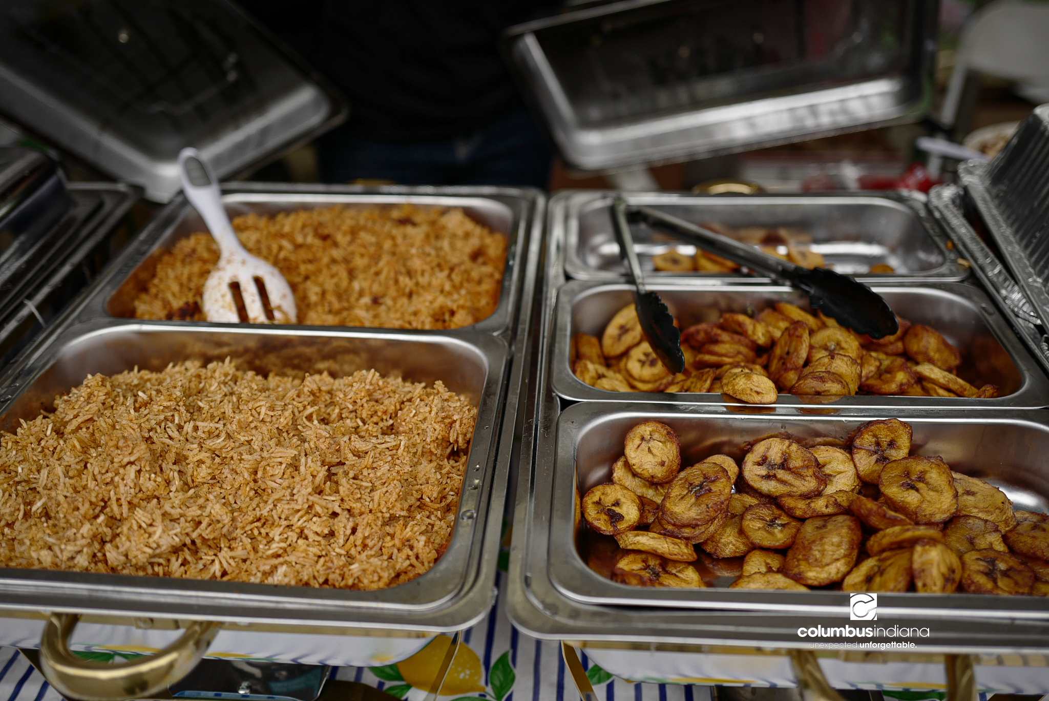 Rice and chicken sit in stainless steel serving trays.